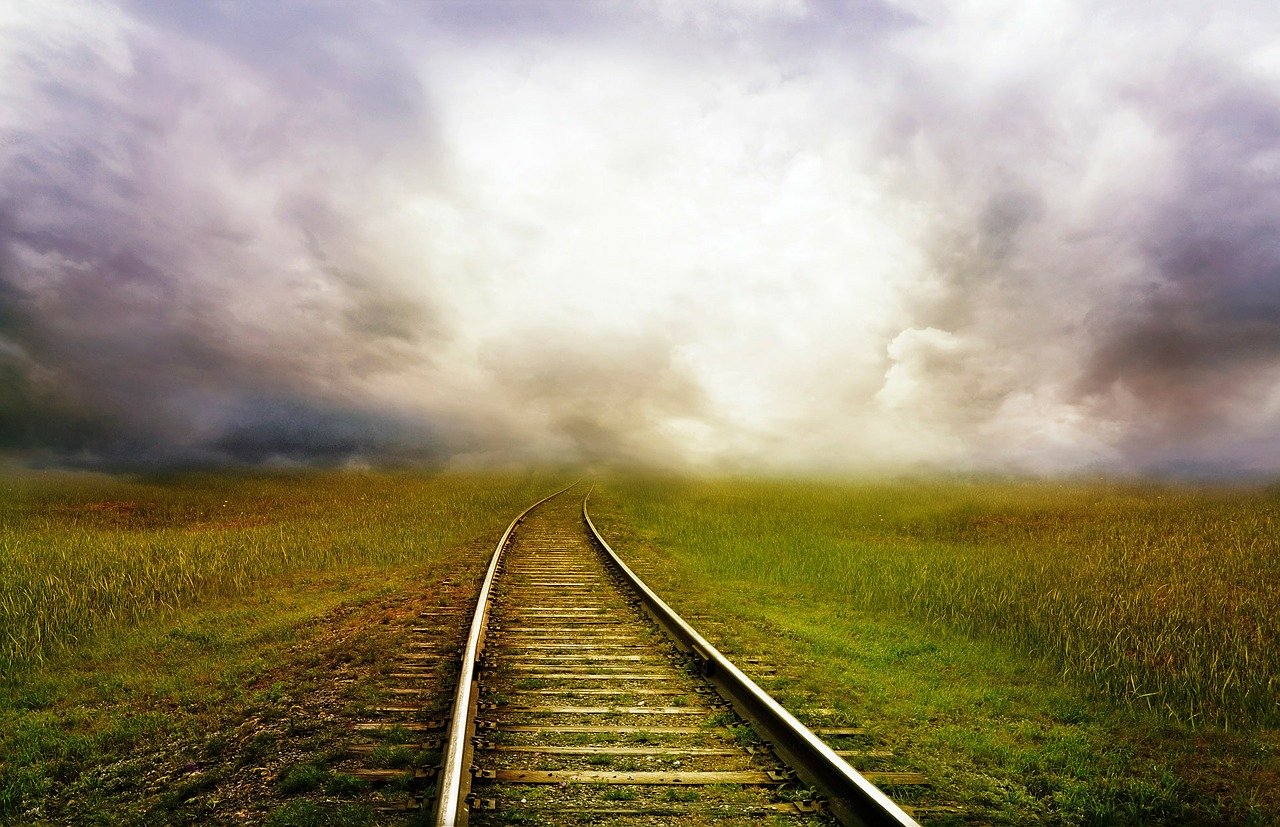 Railroad tracks leading into the distance with gray clouds overhead